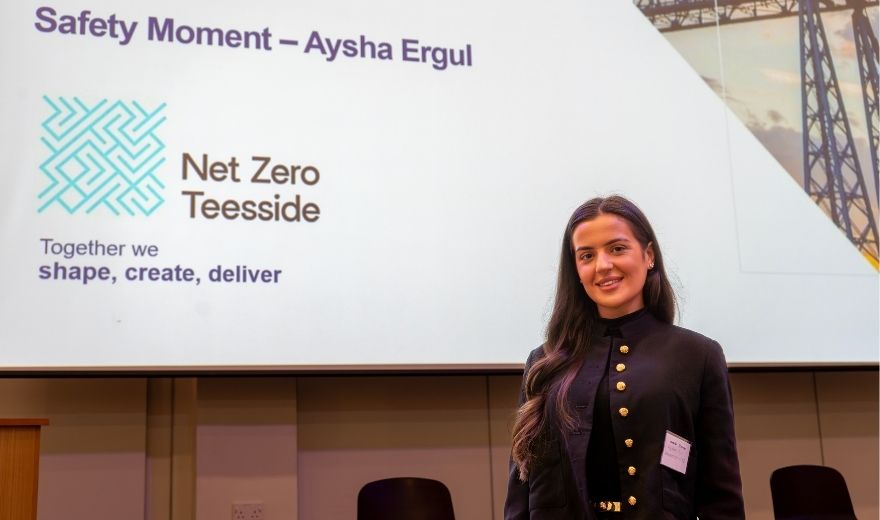 Aysha standing in front of a display screen at a net zero seminar