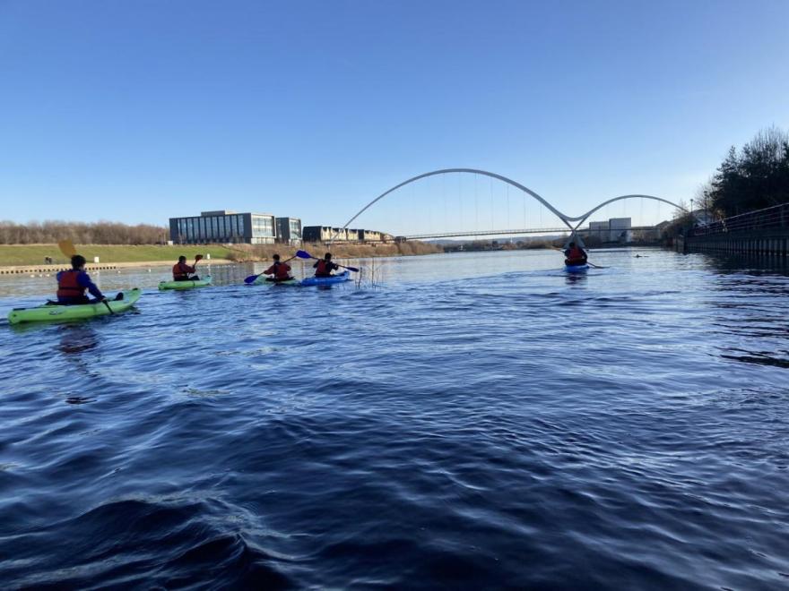 Students enjoying kayaking on the river tees